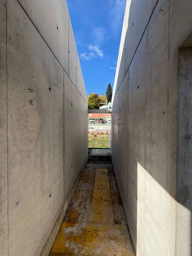 Passage étroit entre deux murs en béton, ouvert sur le ciel