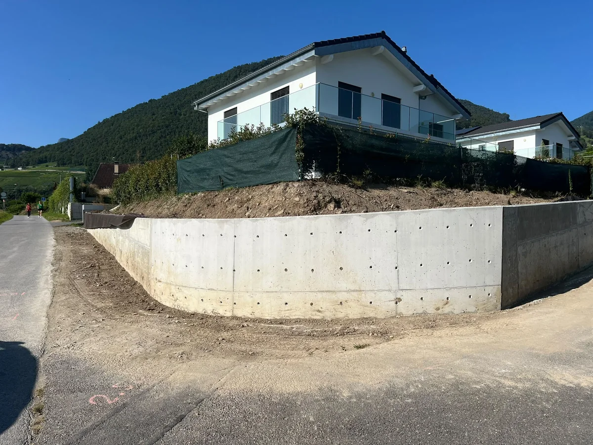 Mur de soutènement en béton devant une maison sur un terrain en pente